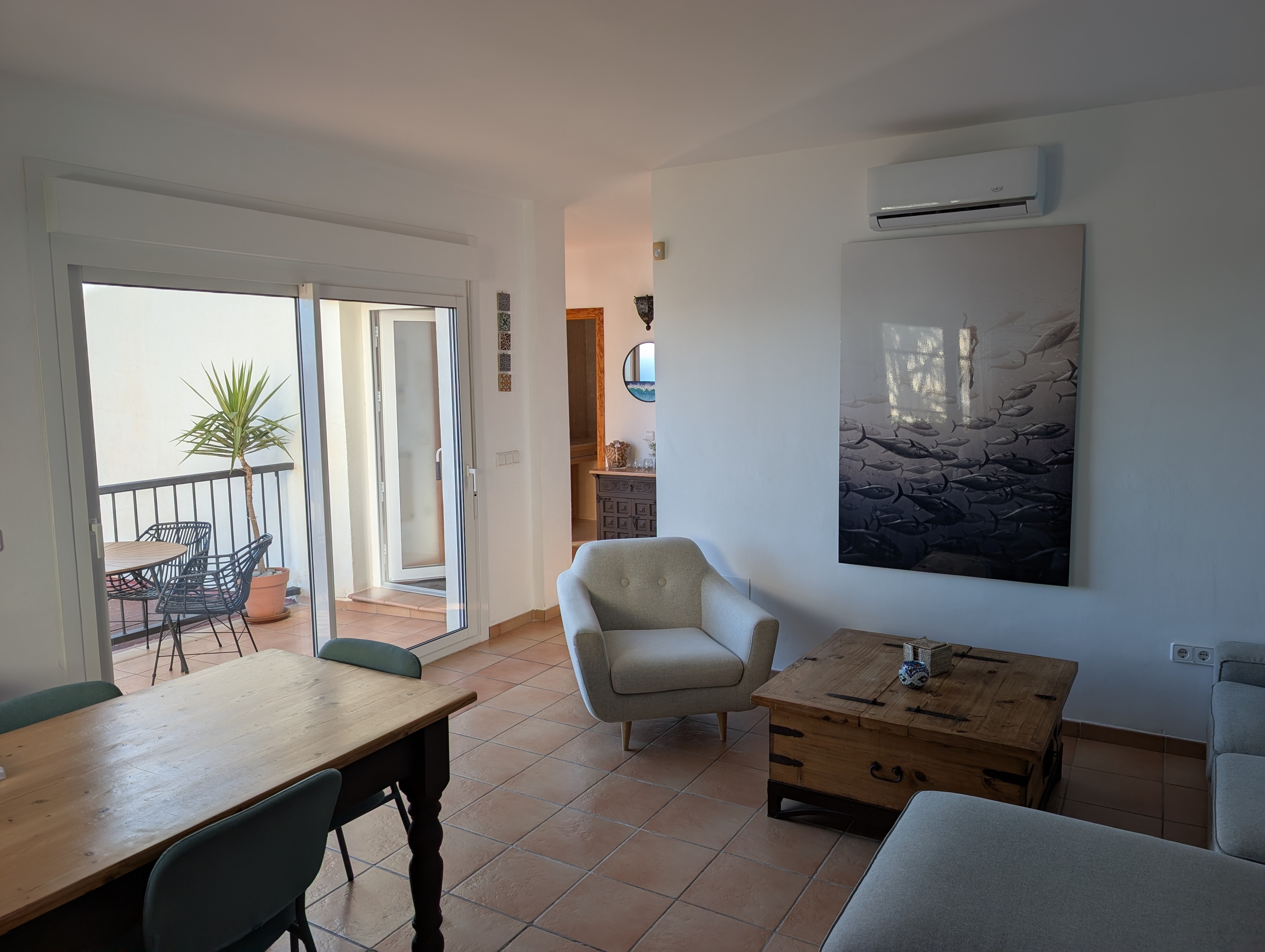 Gezellige woonkamer van Casa Larimar in Fuentes de Almuñécar, met een sfeervolle eethoek, veel natuurlijke lichtinval en een schuifpui naar het terras met zeezicht