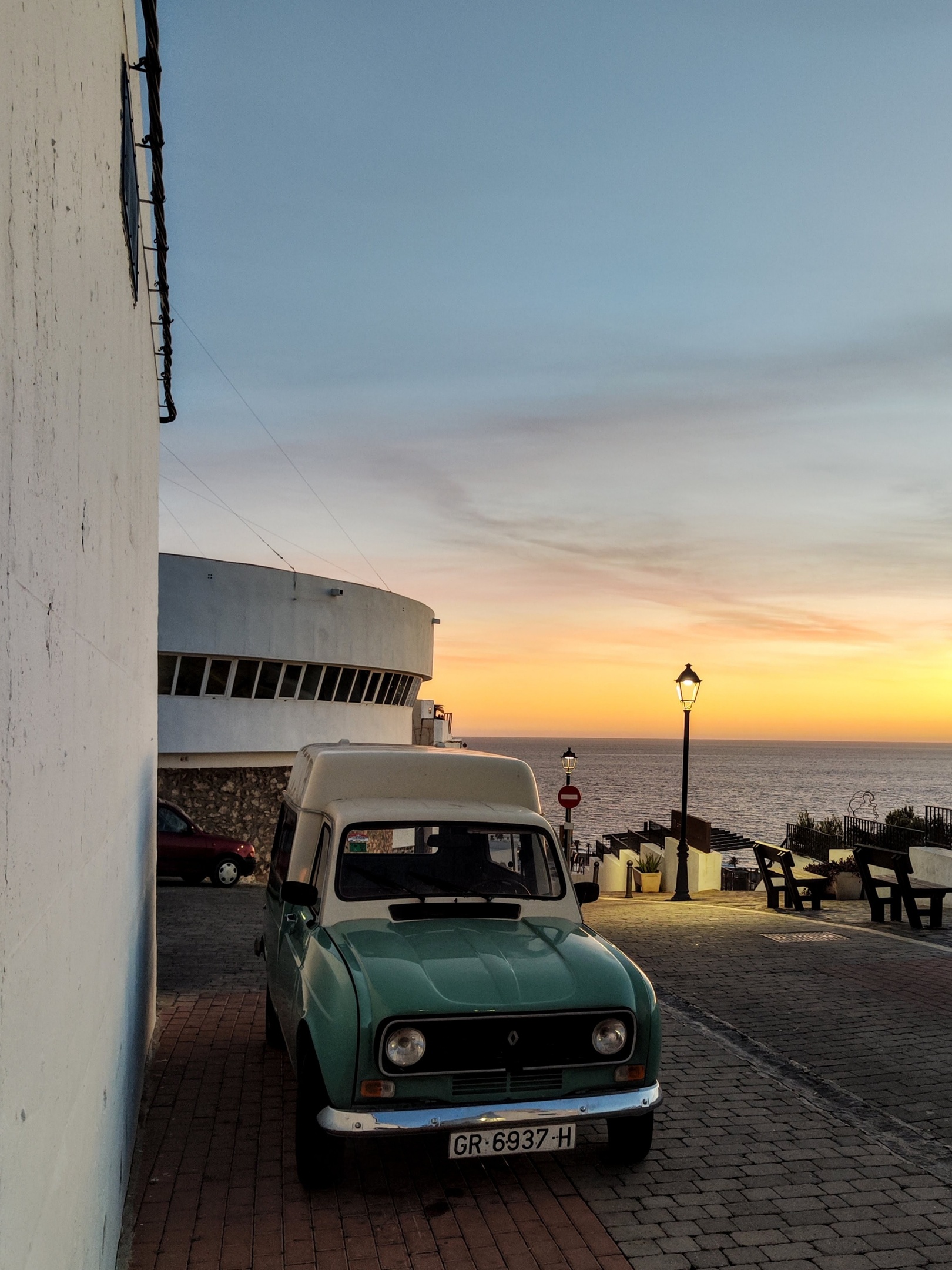 Wit-groene Renault 4 F6 Furgoneta in het casco histórico van Salobreña, met Radio Salobreña, ouderwetse straatlantaarns en de Middellandse Zee tijdens golden hour, oranje gloed boven de zee