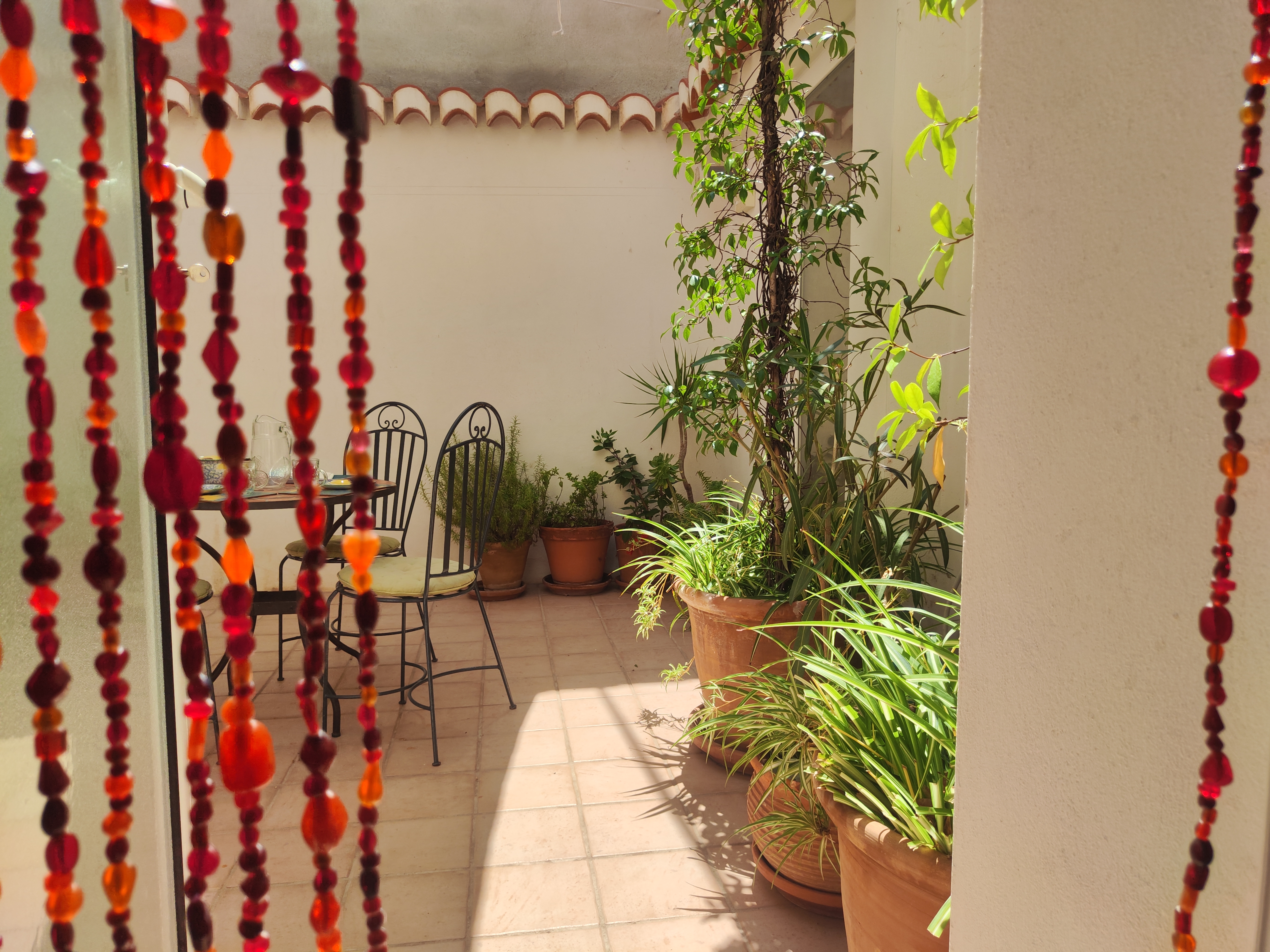 Knusse Andalusische patio van Casita Klein Zwitserland in de Lecrínvallei, met mozaïektafel en terracotta potten met planten. Een sfeervolle plek om te ontbijten voor een wandeling in de Alpujarra of de Sierra Nevada.