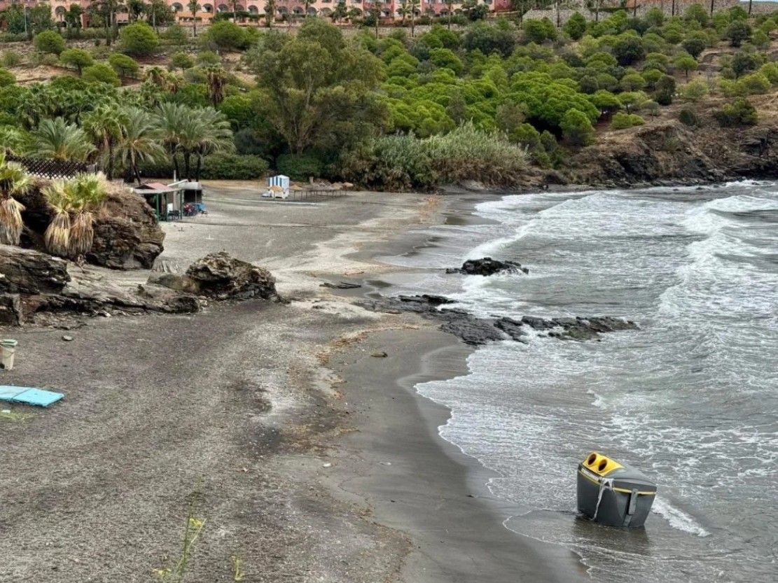 Vuilcontainer voor plastic verpakkingen (geel en grijs) meegesleurd door herfststorm in Rambla Caballero, teruggevonden op strand La Galera, Almuñécar