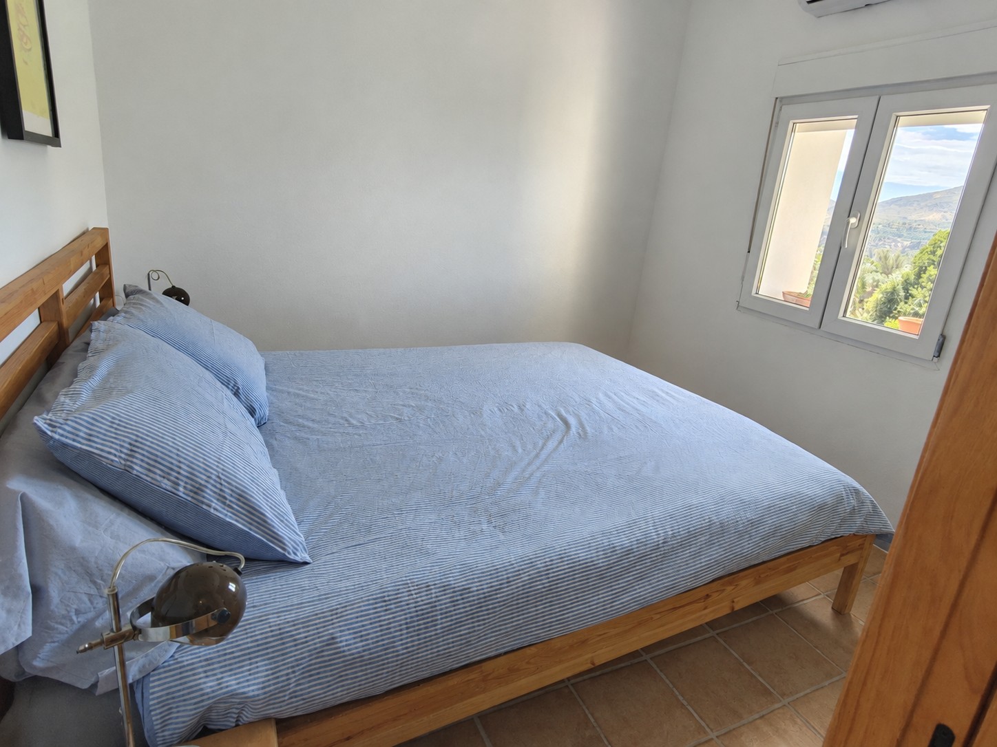 Kleine slaapkamer van Casita Klein Zwitserland met een tweepersoonsbed (1.60 x 2.00), kastruimte, airco voor verwarmen en koelen, en uitzicht op de omgeving van de Lecrínvallei.