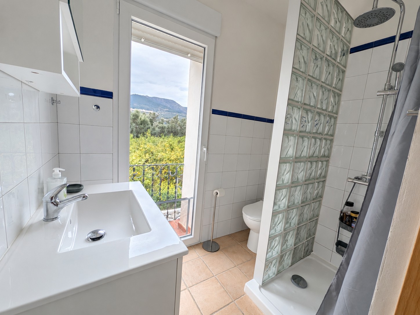 Badkamer van Casita Klein Zwitserland met douche, wc, wastafel en een Frans balkon dat uitkijkt over de omgeving van de Lecrínvallei