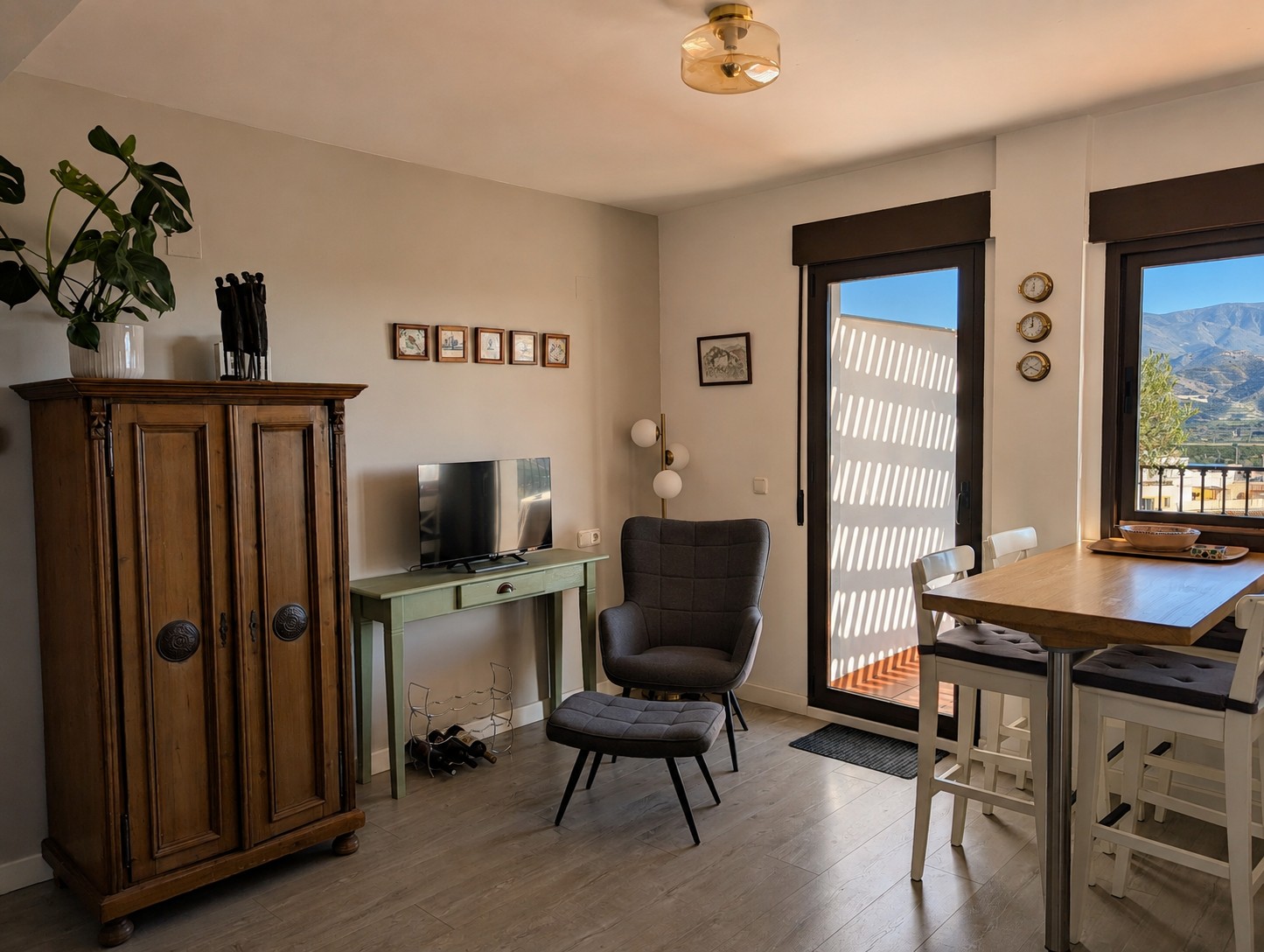 Gezellig hoekje van de woonkamer in Ático Lolapaluza, met antieke kast, fauteuil met voetenbank, planten en glazen deur naar het panoramaterras