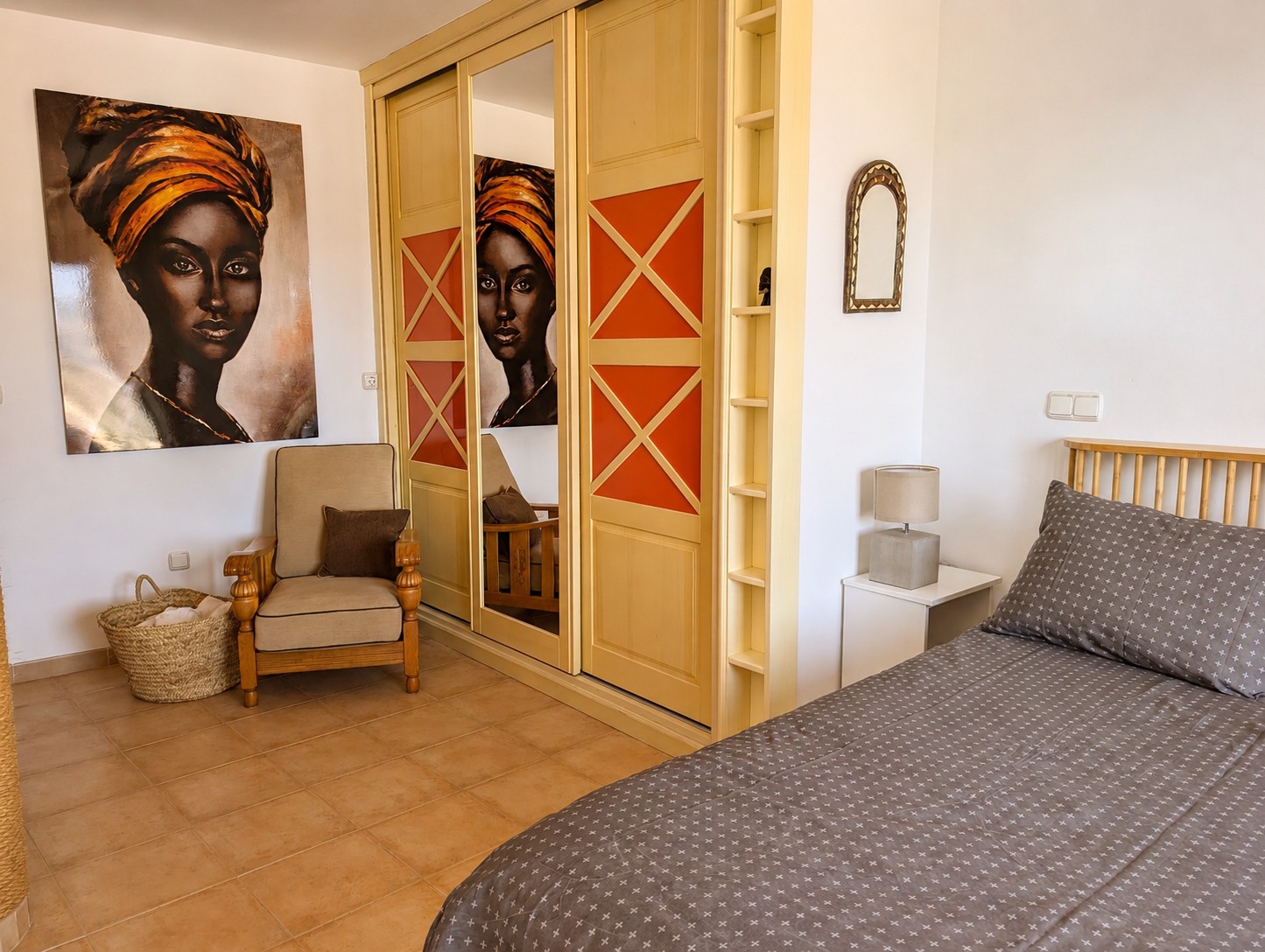 Slaapkamer van Ático Lolapaluza, met comfortabel tweepersoonsbed, kunstwerk aan de muur, ruime inbouwkasten met spiegel en antieke fauteuil