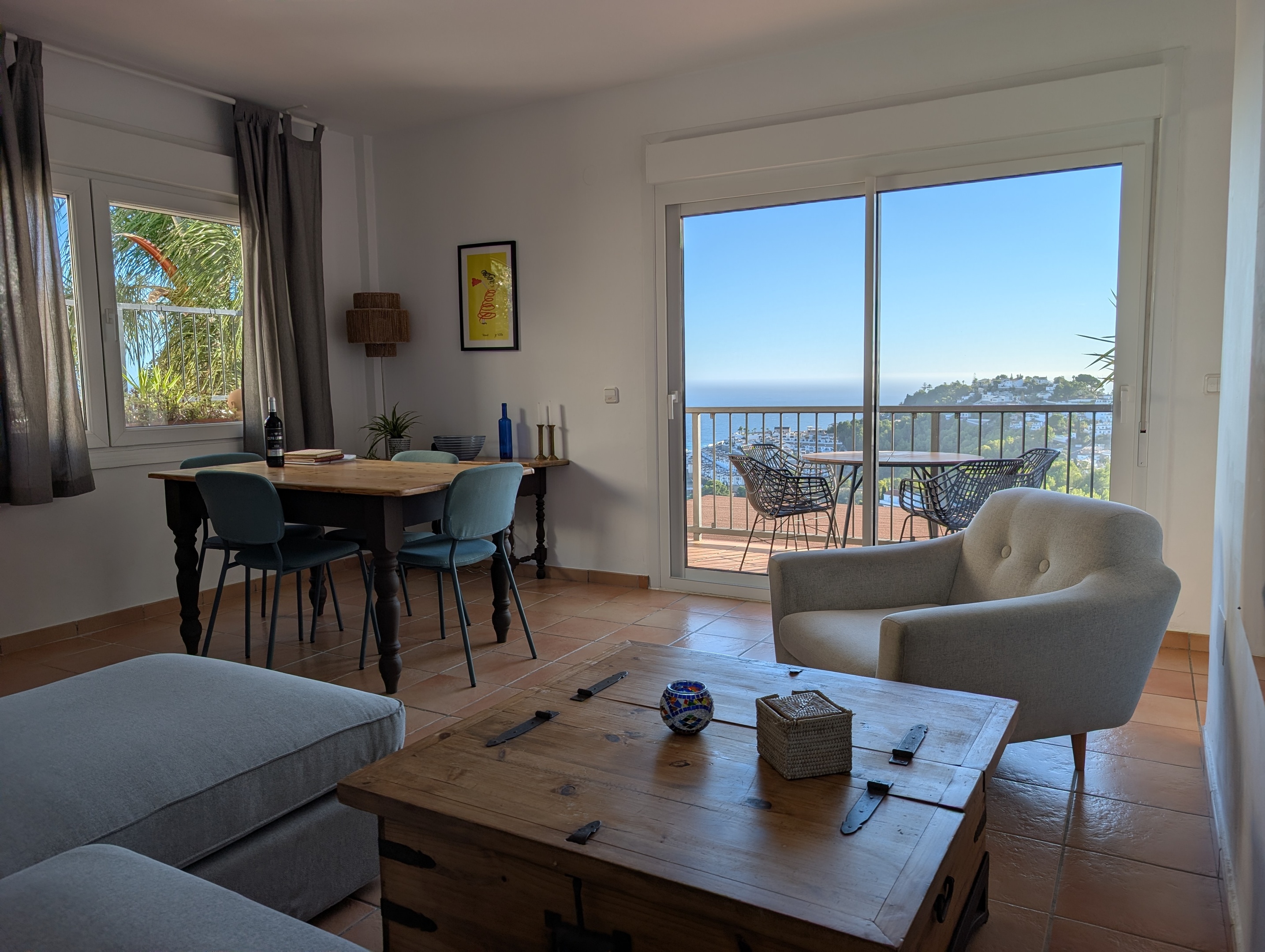 Lichte en ruime woonkamer van Casa Larimar in Almuñécar, met eethoek en zithoek. De schuifpui geeft toegang tot het terras met panoramisch zeezicht. Gelegen in de urbanisatie Fuentes de Almuñécar aan de Costa Tropical, een perfecte plek om te ontspannen en te genieten van de kust en het mediterrane klimaat.