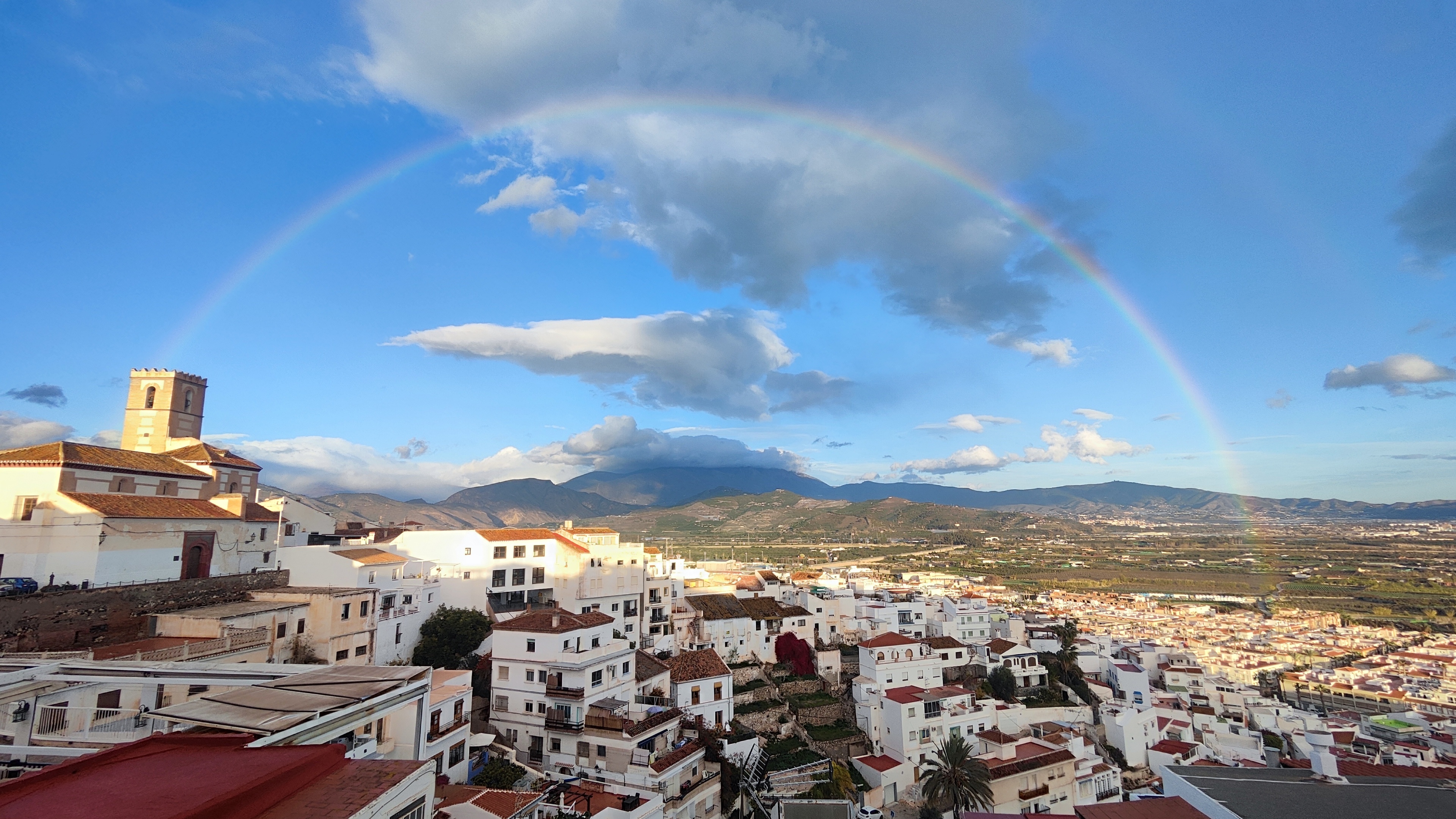 Uitzicht vanaf Ático Lolapaluza op de kerk van Salobreña, het historische centrum en een regenboog boven de vega die de Sierra met de Costa Tropical verbindt.