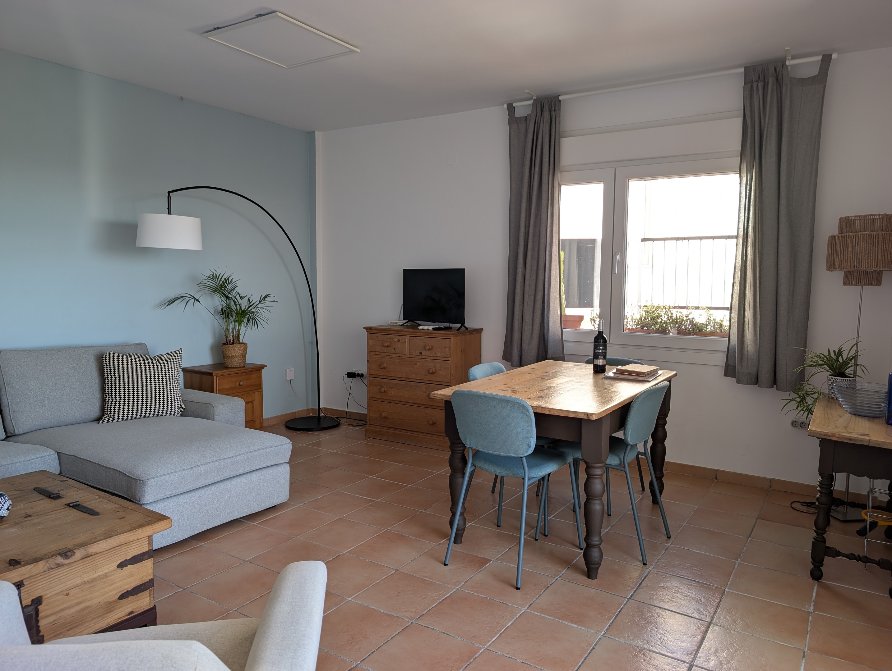 Binnenkomst in Casa Larimar, met een sfeervolle woonkamer, groene planten en een comfortabele loungebank. De Android TV biedt de mogelijkheid om eigen apps te installeren of te casten. Door de schuifpui valt veel licht binnen en is er direct toegang tot het terras met zeezicht. Een heerlijke plek om te ontspannen aan de Costa Tropical