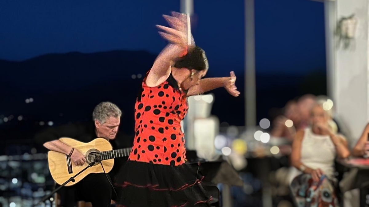 Victoria Macías Costela, flamencodanseres in een rood-zwarte jurk met zwarte polka dots, vastgelegd in een krachtige dansbeweging met vloeiende armbewegingen, dansend in Restaurante La Traviesa