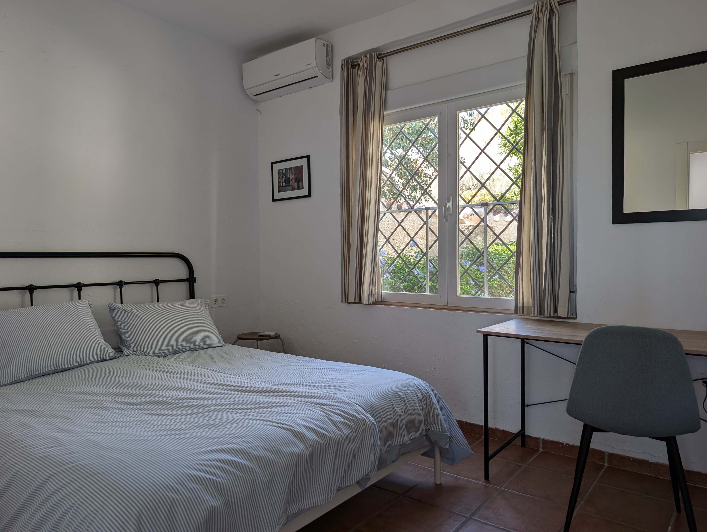 De masterbedroom van Villa Merise biedt een comfortabel bed met Auping-matrassen en topper (1.60 x 2.00), een werkplek met snelle 600 Mbps wifi, een inbouwkast en airco voor zowel verwarming als verkoeling. Gelegen aan de voorzijde van het huis met uitzicht op de groene voortuin